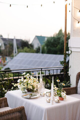 Banquet table is decorated with plates, cutlery, glasses and flower arrangements