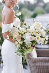 bride in a white wedding dress holding a bouquet of roses, peonies and greenery
