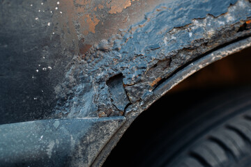 A bodywork fragment of a rusty car fender. Aggressive corrosion. Selective focus