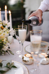 Banquet table is decorated with plates, cutlery, glasses and flower arrangements