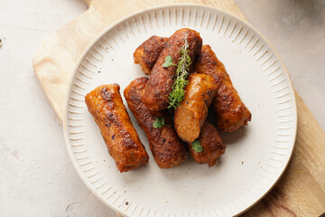 Traditional south european skinless sausages cevapcici made of ground meat and spices on white plate on light wooden board, with thyme and watercress salad