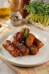 Traditional south european skinless sausages cevapcici made of ground meat and spices on white plate on light wooden board, with thyme and watercress salad