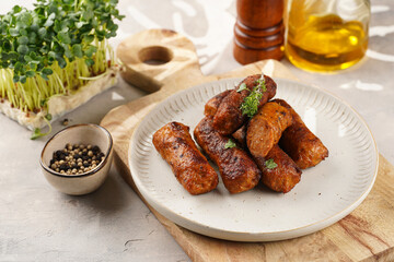 Traditional south european skinless sausages cevapcici made of ground meat and spices on white plate on light wooden board, with thyme and watercress salad