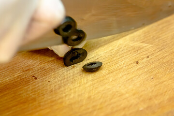 hands hold a shev knife and cuts black olives