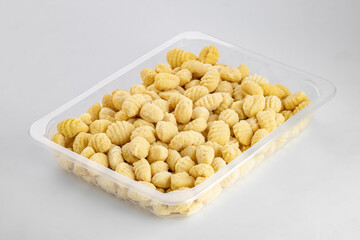 Fresh italian pasta gnocchi in plastic box on white background