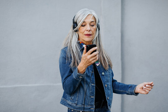 Senior woman with grey long hair wearing denim jacket.