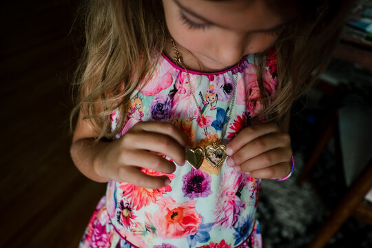 little girl looks at locket necklace