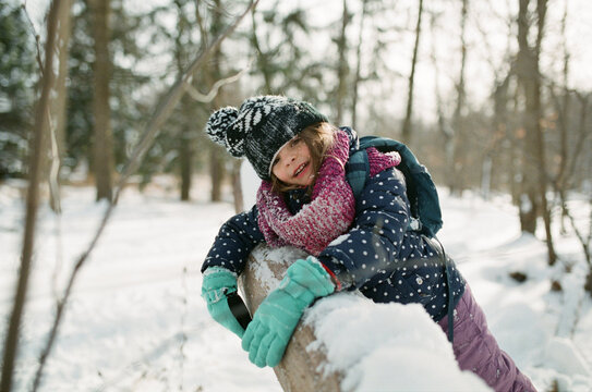 Girl lays on snow covered log