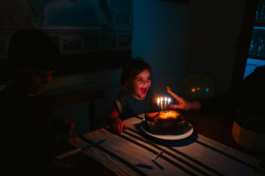 little girl blows out candles on cake