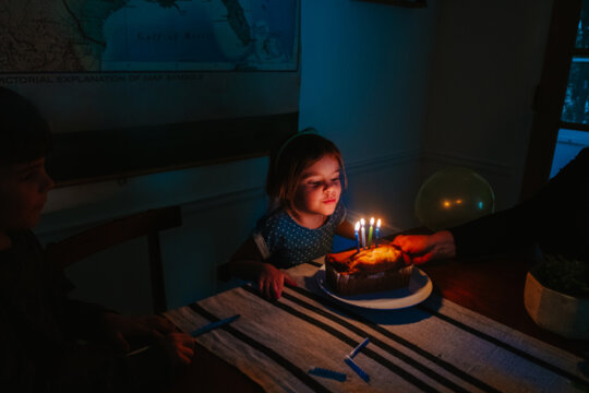 little girl blows out candles on cake