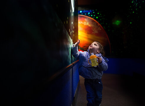 little boy points at paintings of universe