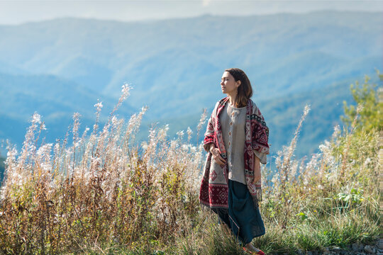 The young woman in traditional clothes among the mountains