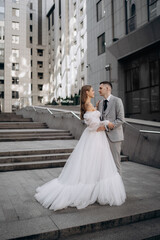 Obraz premium Vertical photo of young couple just married on city background. professional wedding photoshoot stand stairs city outside