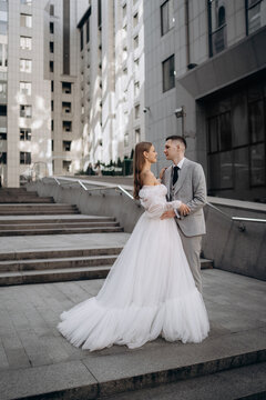Vertical photo of young couple just married on city background. professional wedding photoshoot stand stairs city outside