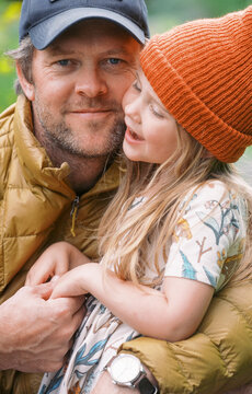 father and daughter snuggle outdoors