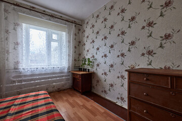 Example of Old Soviet Russian poor interior in Khruschev House. Aged  sideboard, table, chairs. Shabby floor. Tattered wallpaper on the wall. Apartment of pensioners. Selective focus.
