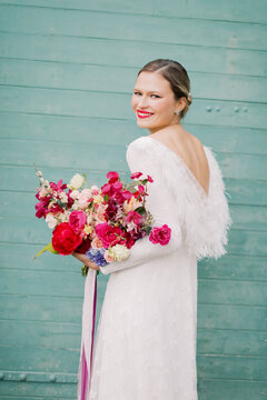 Women In A Wedding Dress Holding Vibrant Flowers 