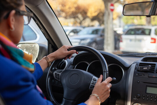 woman driving a car in a parking lot, hands on steering wheel