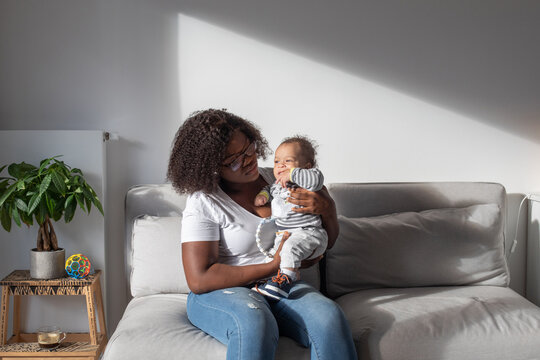 serious mother holding small baby at home, black woman with child