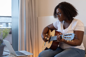 learn online, black woman learning to play guitar online at home