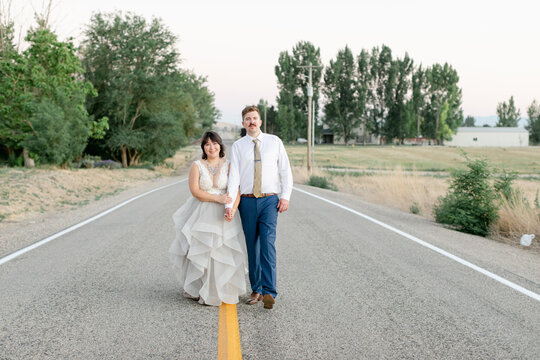 Couple Walking on Road in Wedding Attire