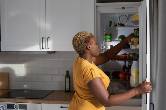 food in refrigerator, woman picking bottle from fridge in the kitchen