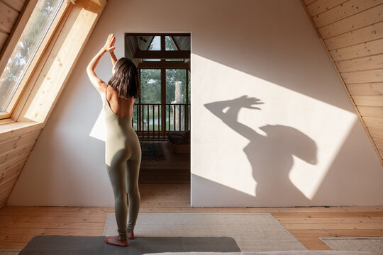 Brunette meditating in sunlit attic at home
