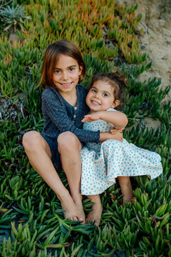 Young sisters sitting patch of ice plants