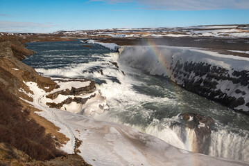 Scenic view of the upper stages of the mighty Gullfoss waterfall in winter, with a beautiful small rainbow, Golden Circle Route, Iceland