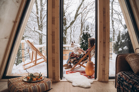 Woman with dog admiring nature on terrace of A frame hut