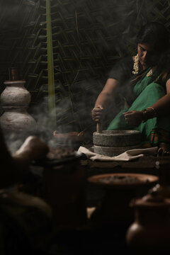 A woman preparing millet flour and another woman making roti