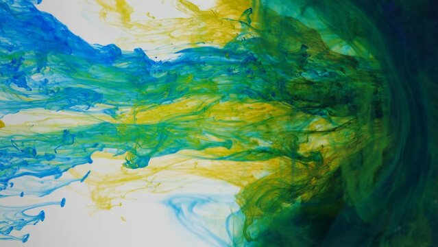 Mixing blue and yellow colors on a white background. Injection of paints into a transparent space.