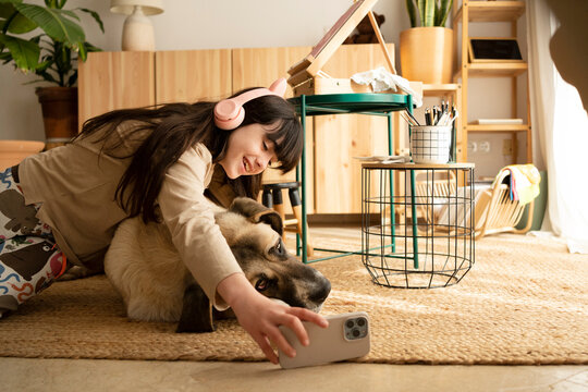 Girl taking selfie with her dog at living room floor