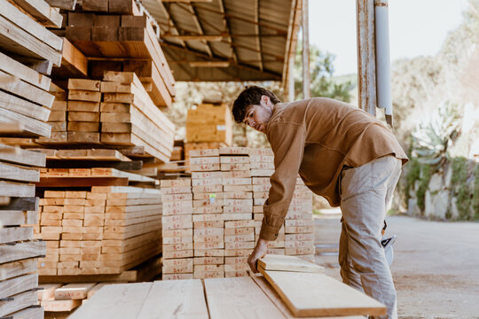 Portrait of man sawing Wooden boards at lumber mill in a barn