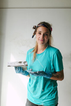 Portrait of woman plasterer with a spatula near the wall