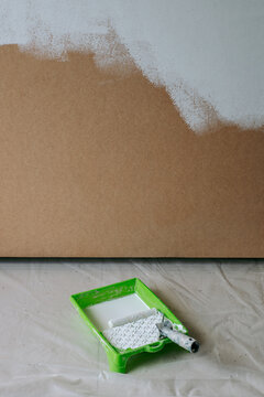 Roller for painting walls lies in a plastic tray near the wall 