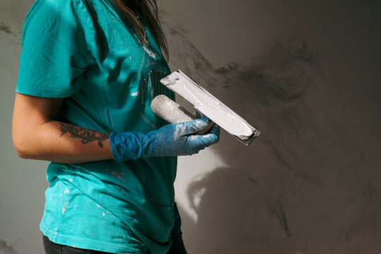 Portrait of woman plasterer with a spatula near the wall
