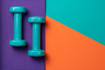 green dumbbell and yoga mat on table, fitness healthy and sport concept