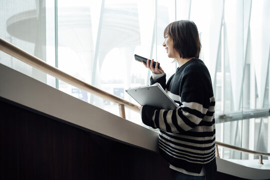 Young woman using smartphone and standing on stairs