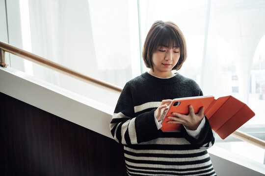 Young asian girl using digital tablet on the hall way stairs