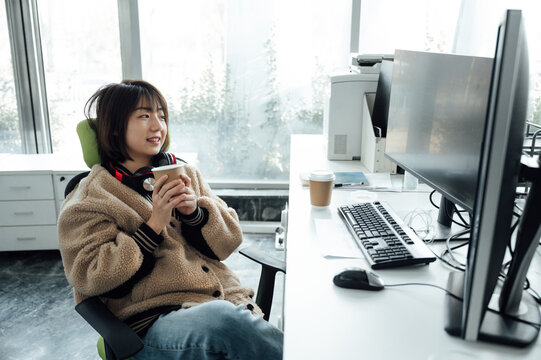 Young business woman holding coffee cup in office