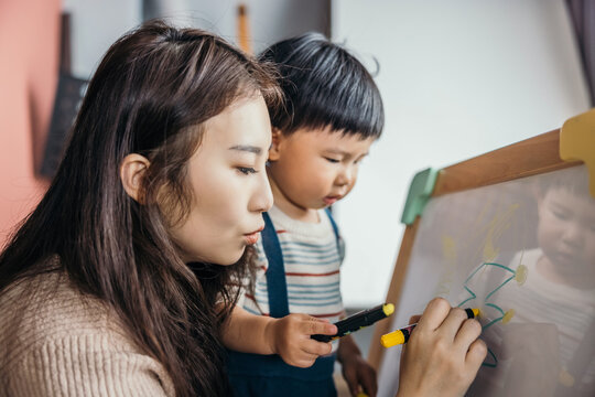 Mother teaching her little baby boy drawing