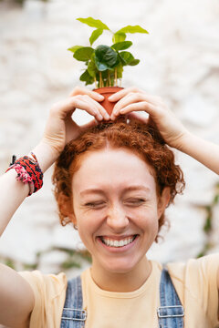 Positive ginger woman with flowerpot on head