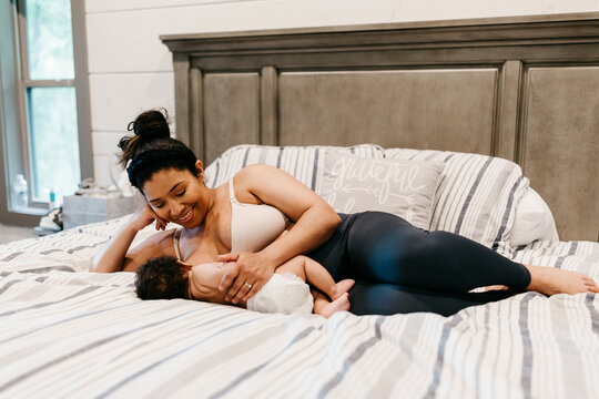 A woman laying down in bed breastfeeding her child