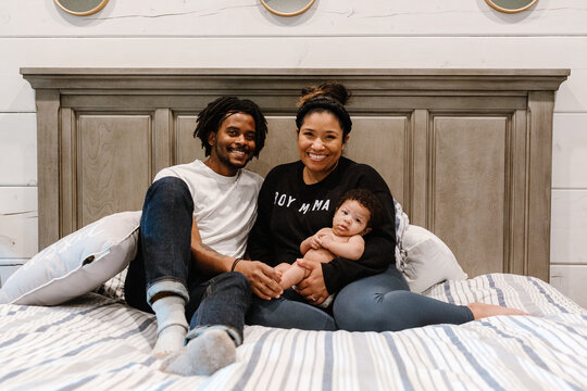 A black mother and father in the bed with their new born son