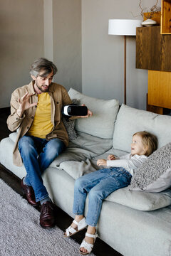 Father showing VR googles to daughter at home
