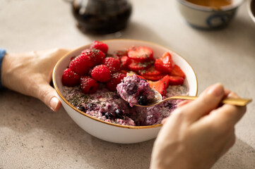 Woman eating healthy overnight oatmeal breakfast with fruit topping