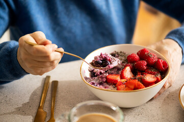 Woman eating healthy overnight oatmeal breakfast with fruit topping