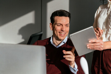 Happy colleague couple using computer and tablet in office desk