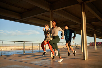 Athletic multiracial friends jogging at seaside